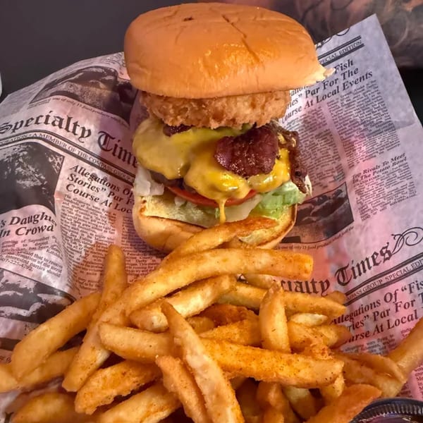 A Stack'd Burger with an onion ring, bacon, cheese, lettuce, and tomato, served with seasoned fries.