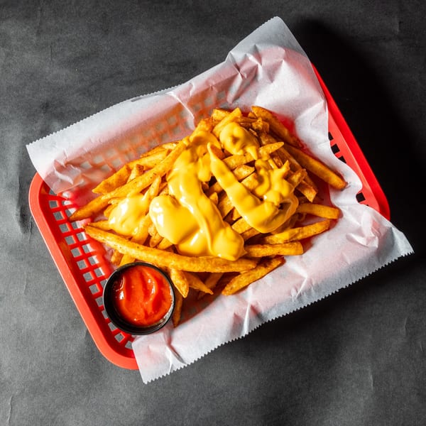 Stack'd Burger's cheesy fries in a red basket with a side of ketchup.